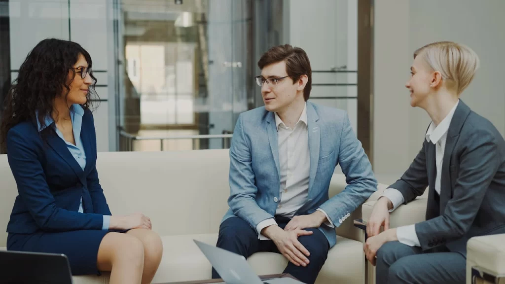 Three professionals in a business meeting, discussing ideas in a modern office environment.